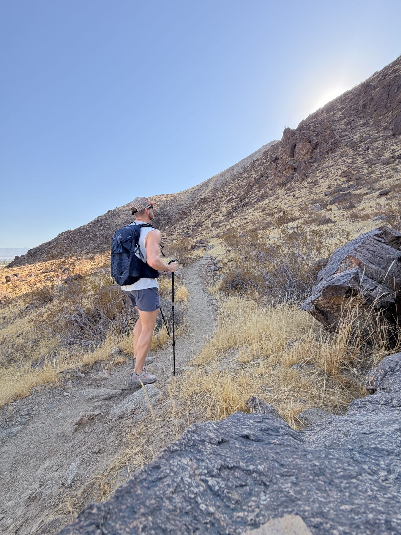 Hiker with Gregory pack and trekking pole ascending a desert trail above Palm Springs